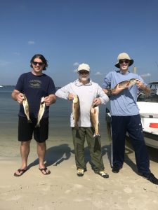 Smiling anglers displaying a trophy redfish aboard Showintail Inshore Charters in Navarre Beach, Florida 