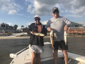 Angler holding a large slot Redfish on shallow grass flats in Navarre FL