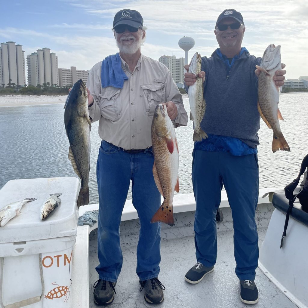 Two anglers holding redfish and speckled trout on Santa Rosa Sound near Navarre Beach