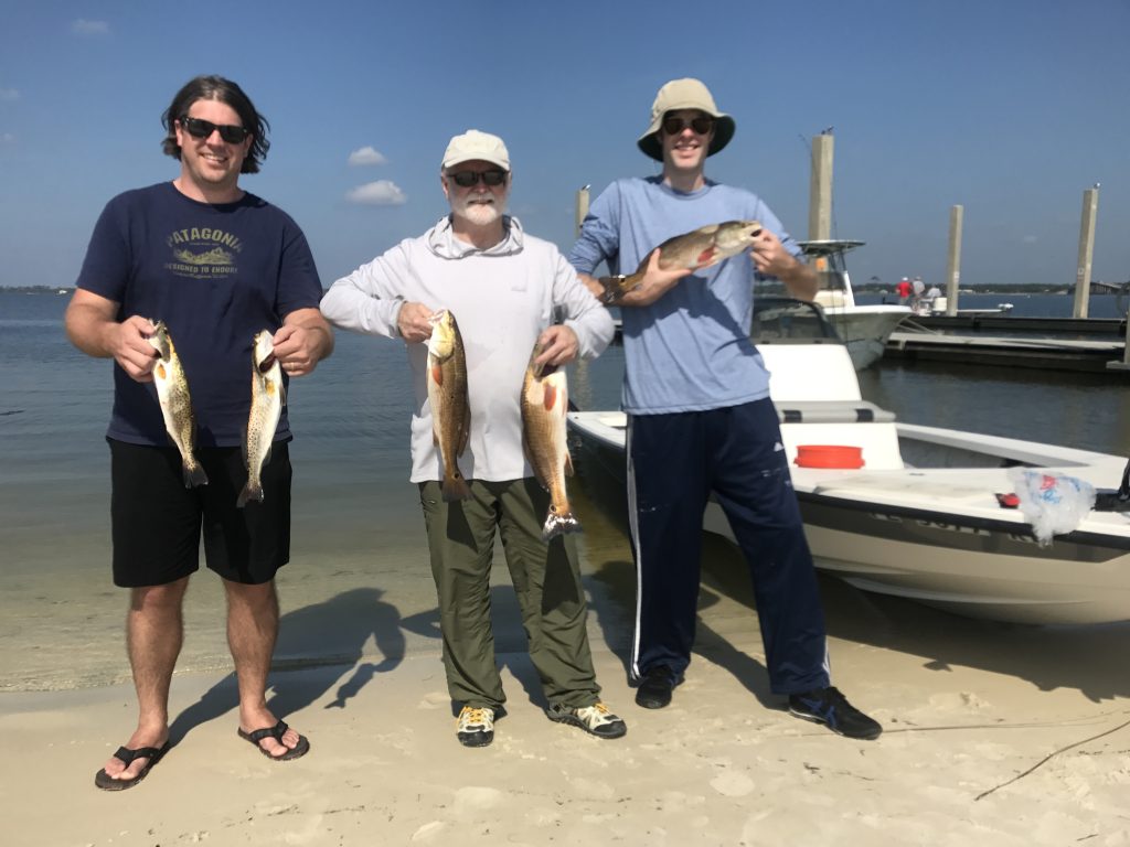 Smiling anglers displaying a trophy redfish aboard Showintail Inshore Charters in Navarre Beach, Florida