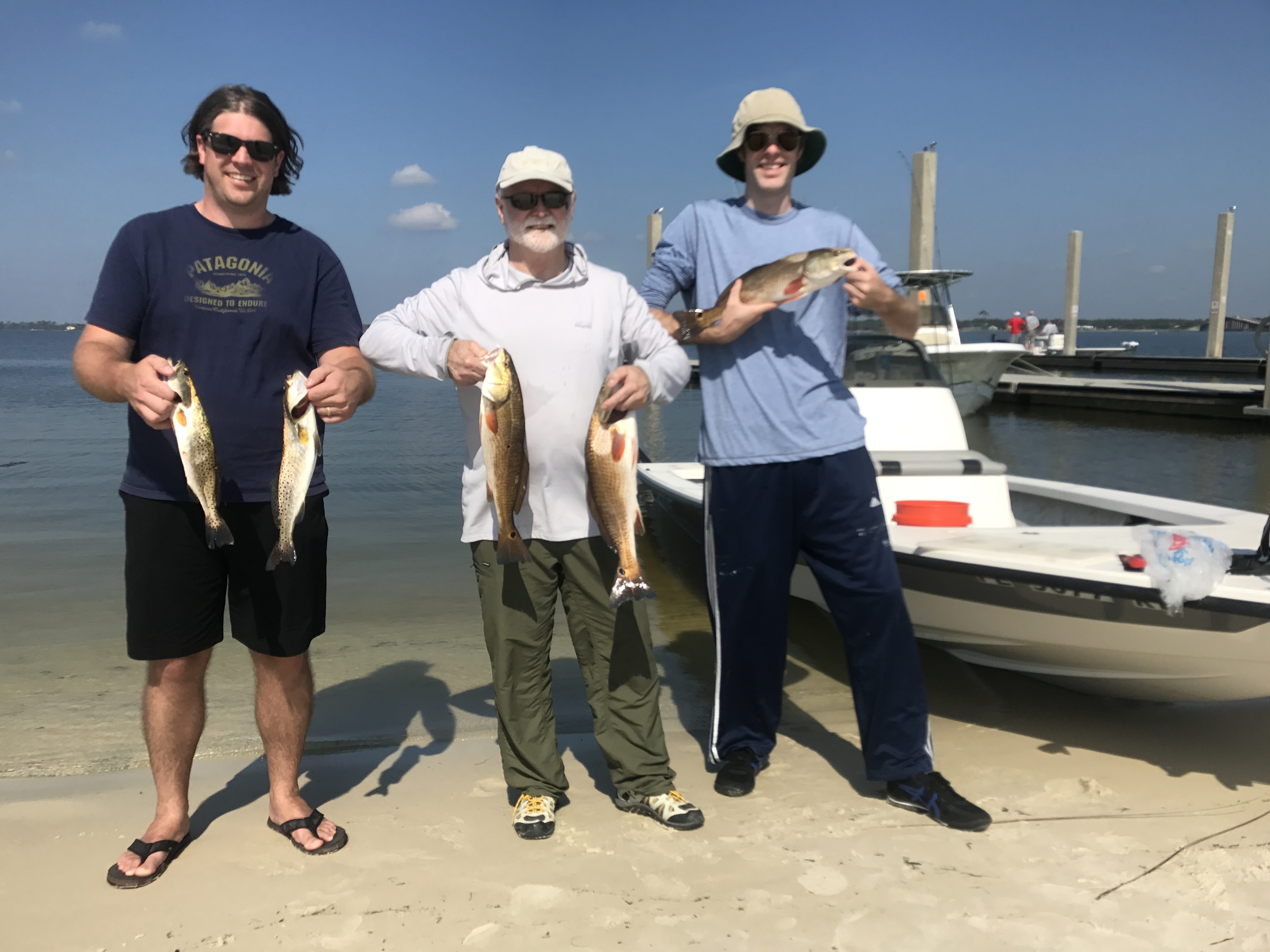 Smiling anglers displaying a trophy redfish aboard Showintail Inshore Charters in Navarre Beach, Florida