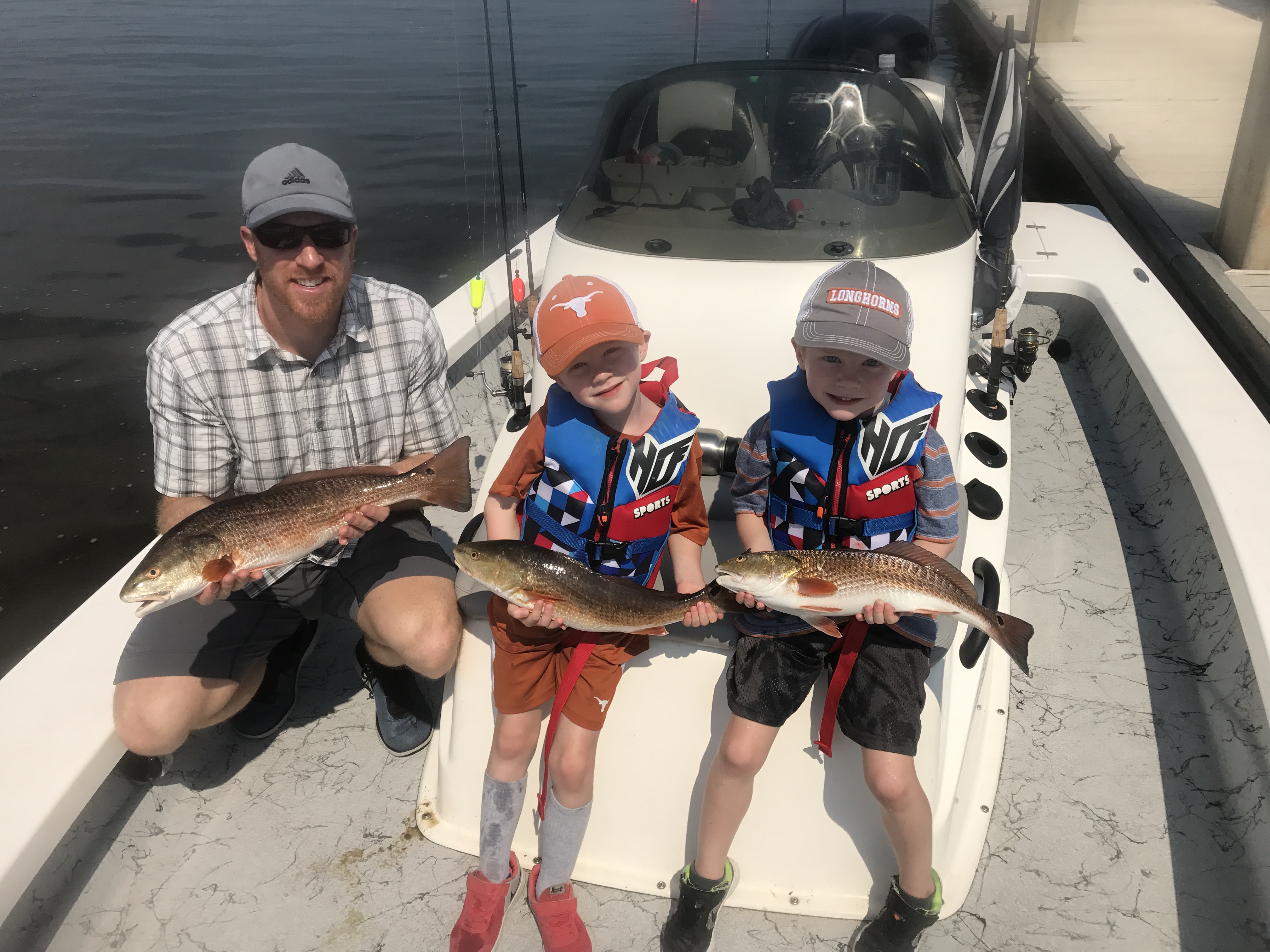 Happy family holding a large Navarre Beach redfish aboard Showintail Inshore Charters