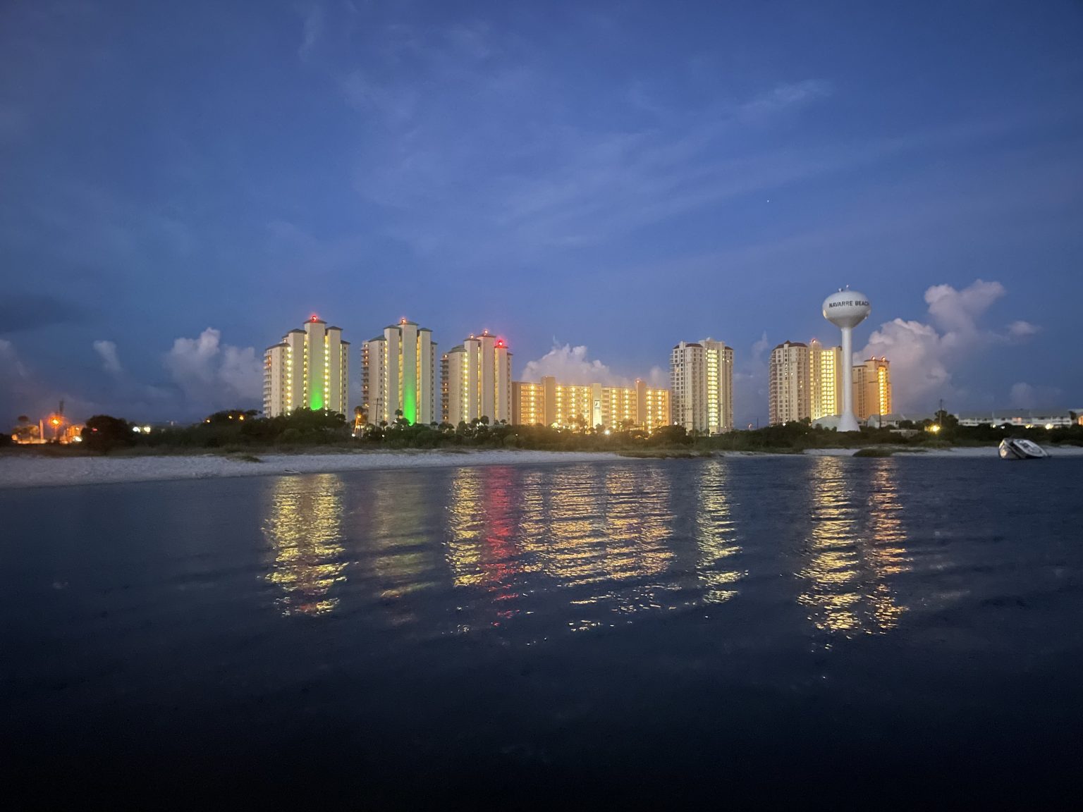 Navarre Beach shoreline lit up at dusk, seen from the water