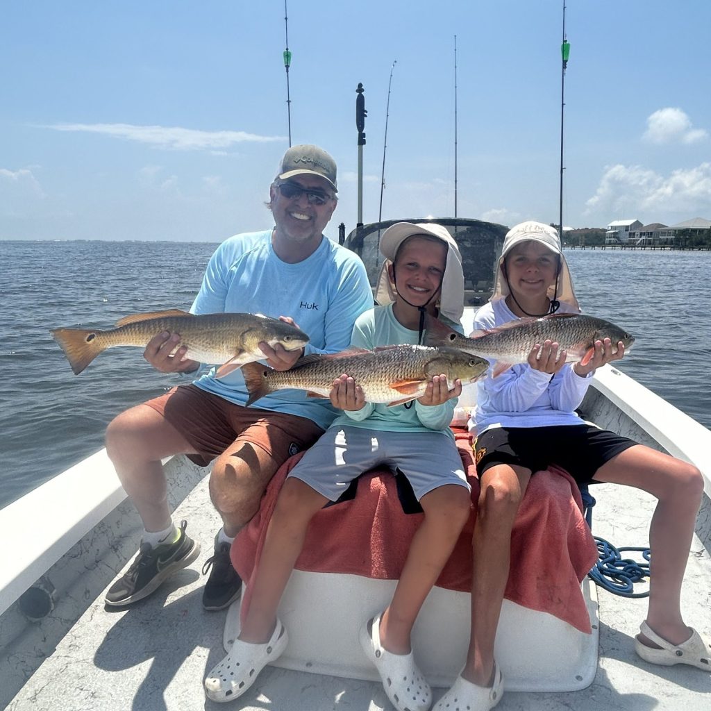 Family smiling with a redfish on a half day charter