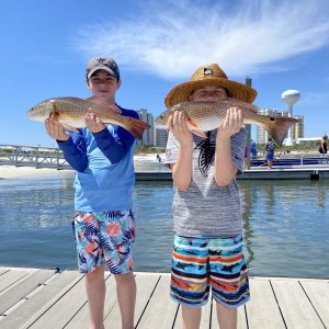 kids holding a two redfish during a 2-hour kids fishing trip with Showintail Inshore Charters in Navarre Beach, Florida