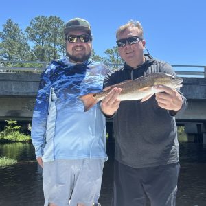 Angler holding a bright redfish caught on a 4-hour inshore charter with Showintail Inshore Charters in the oyster bars off Navarre Beach