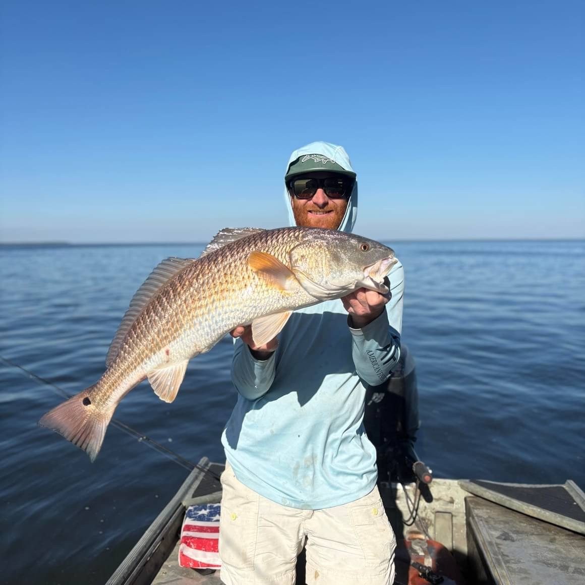 Captain Chris holding a freshly caught redfish on a sunny day in Navarre, Florida with Showintail Inshore Charters