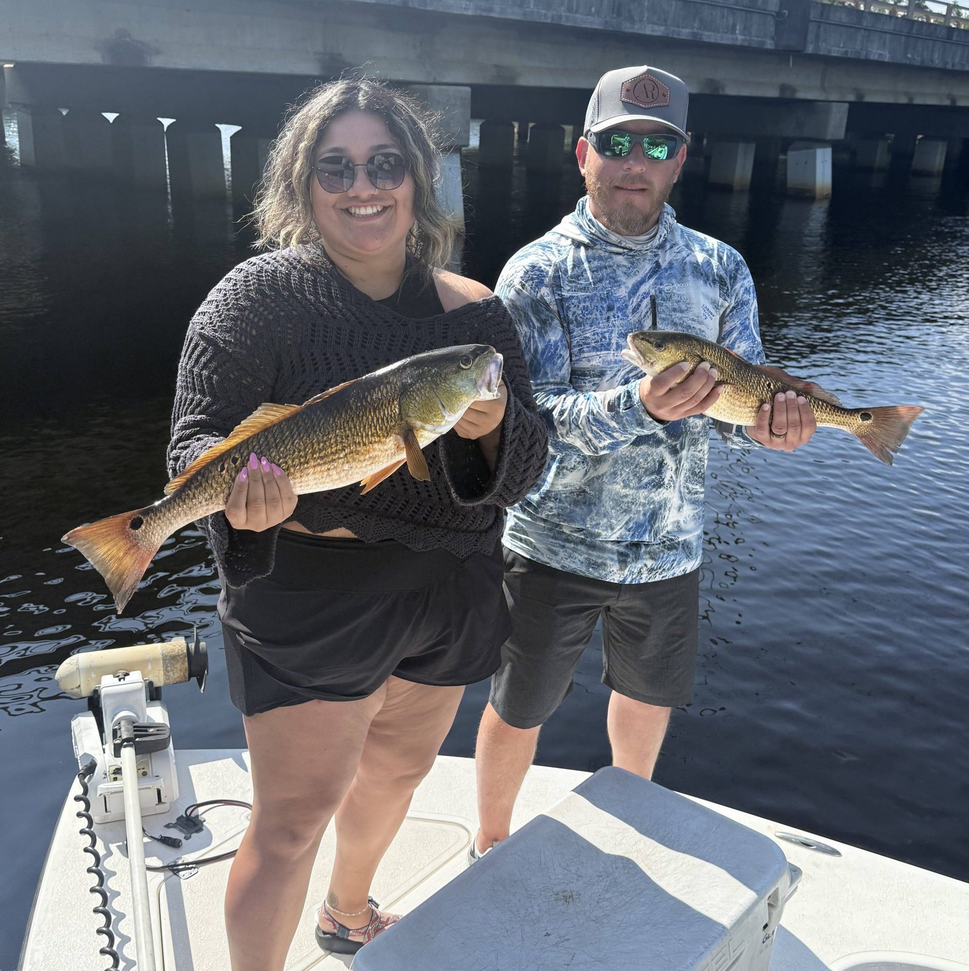 Husband and wife holding a redfish during an inshore fishing charter near Milton, Florida with Showintail Inshore Charters