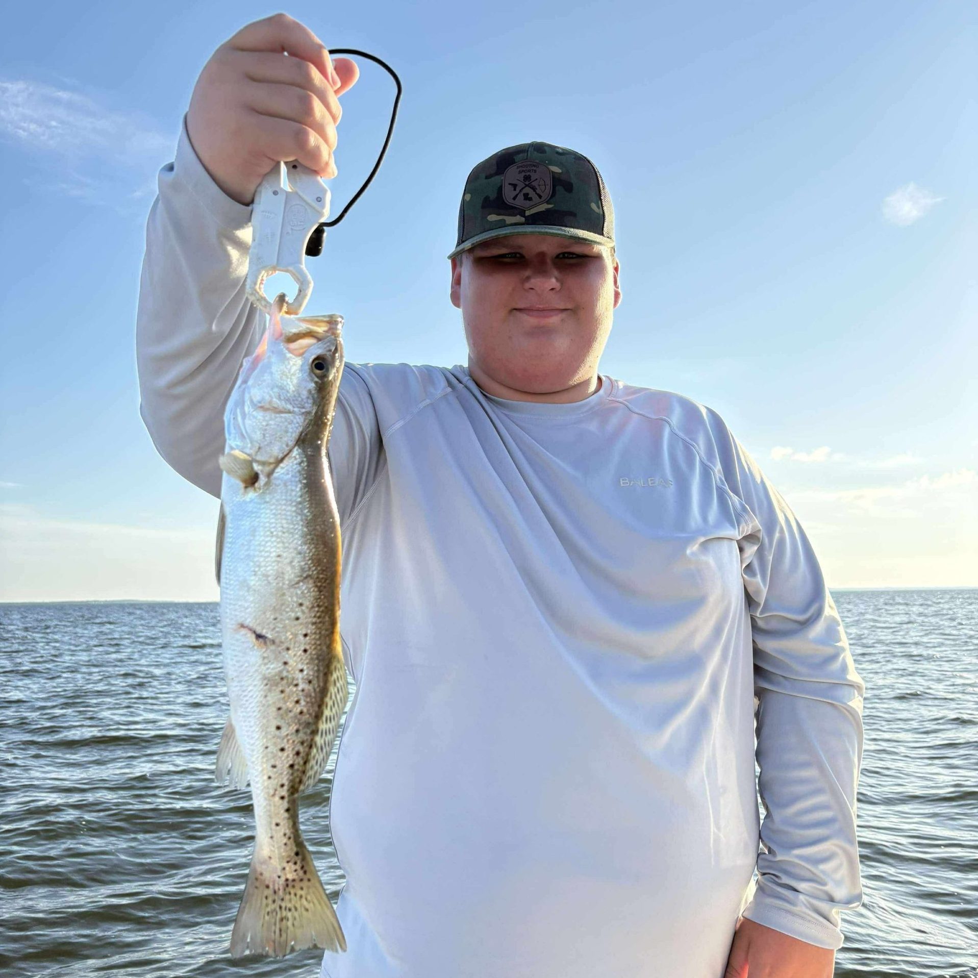 Angler holding a speckled trout during a calm inshore fishing charter on Okaloosa Island with Showintail