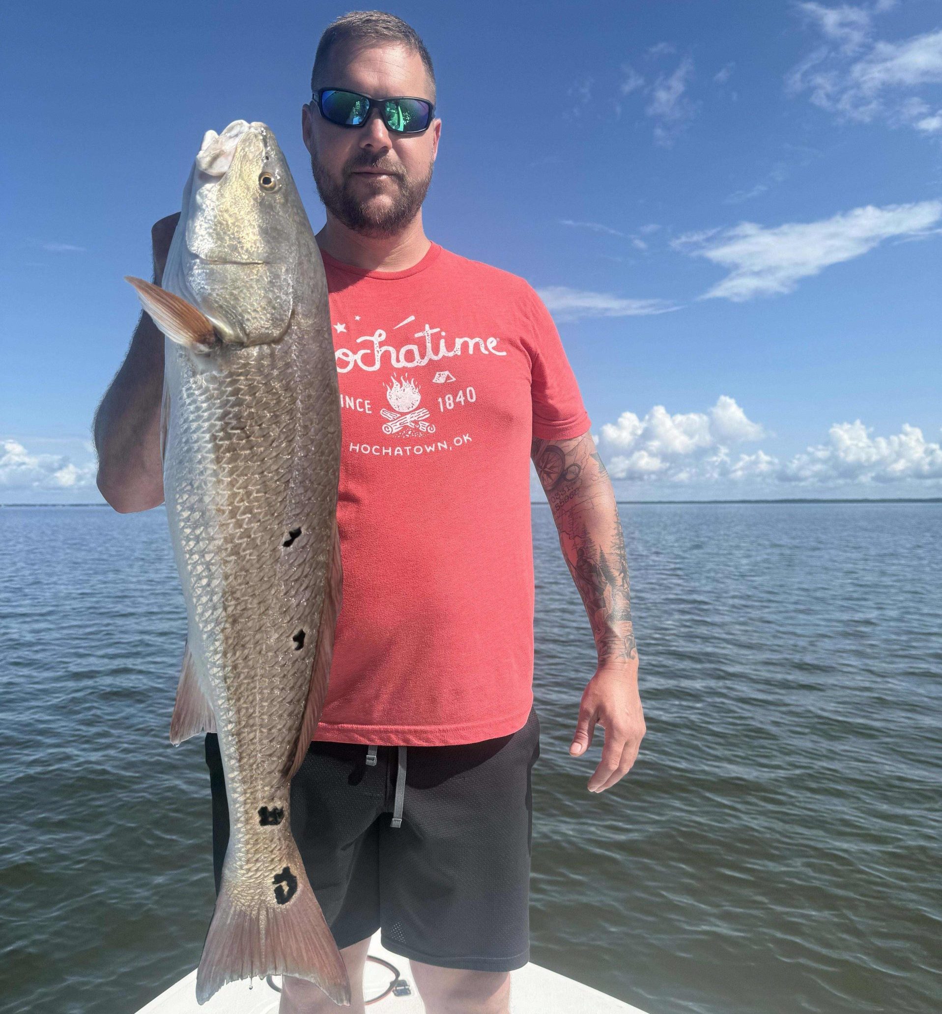 Angler holding a large redfish during a guided inshore charter near Pensacola Beach