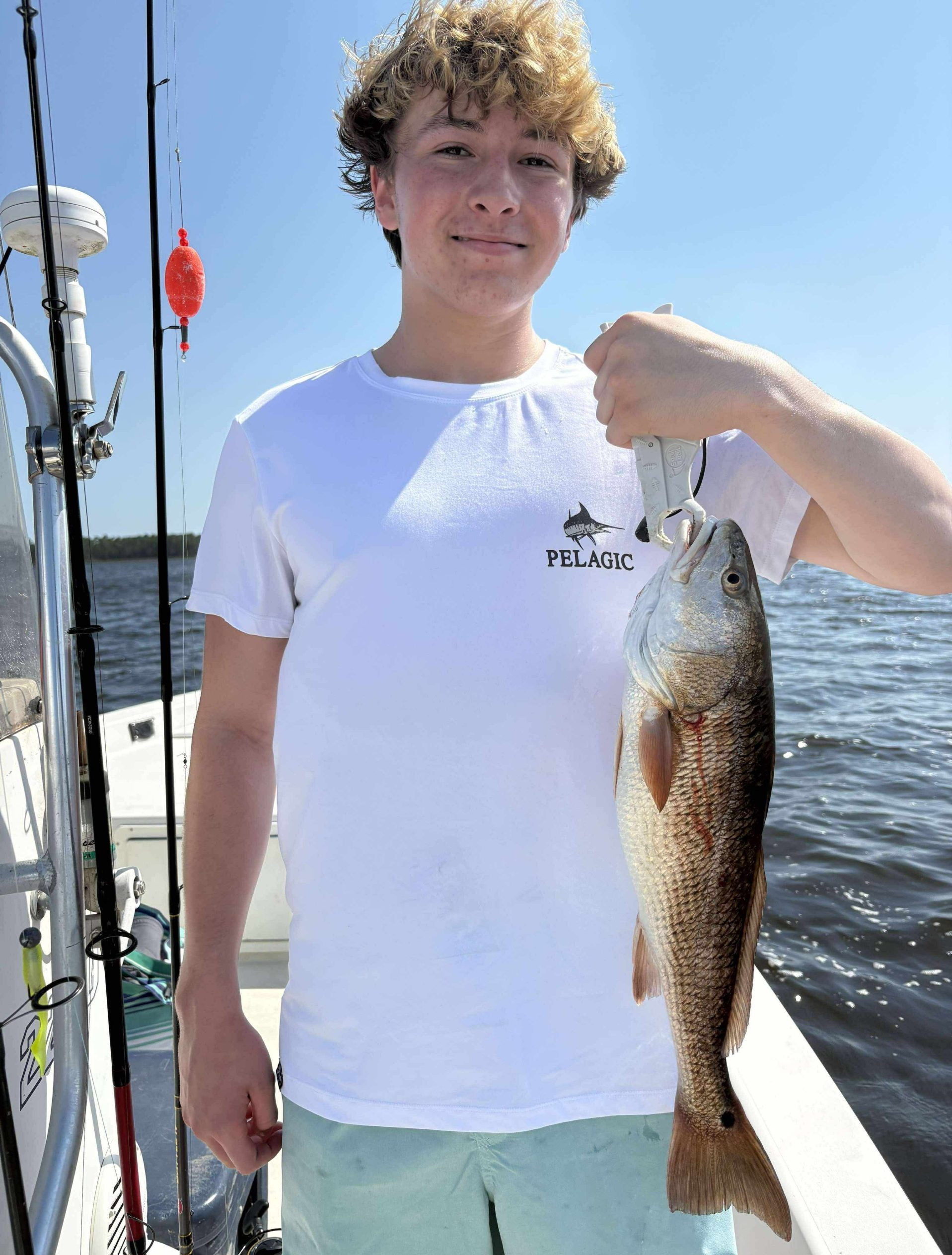 Father and son holding a redfish during an inshore fishing charter near Pace, Florida with Showintail Inshore Charters