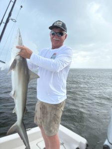 Family fishing charter in Pensacola Beach with kids posing next to a small shark