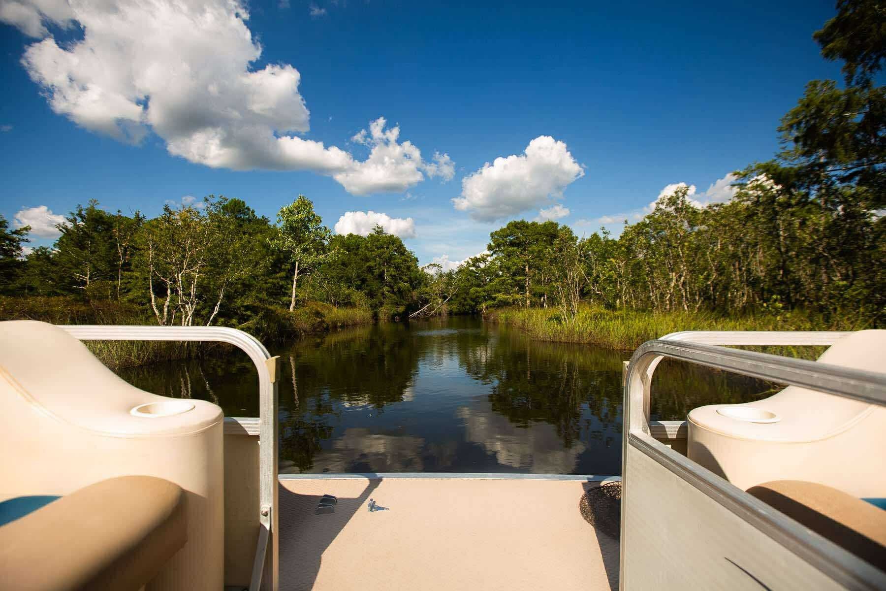 View of a calm river from the bow of a pontoon boat