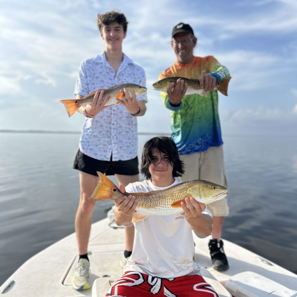 Group holding redfish on a 4-hour half day fishing trip in Navarre, FL
