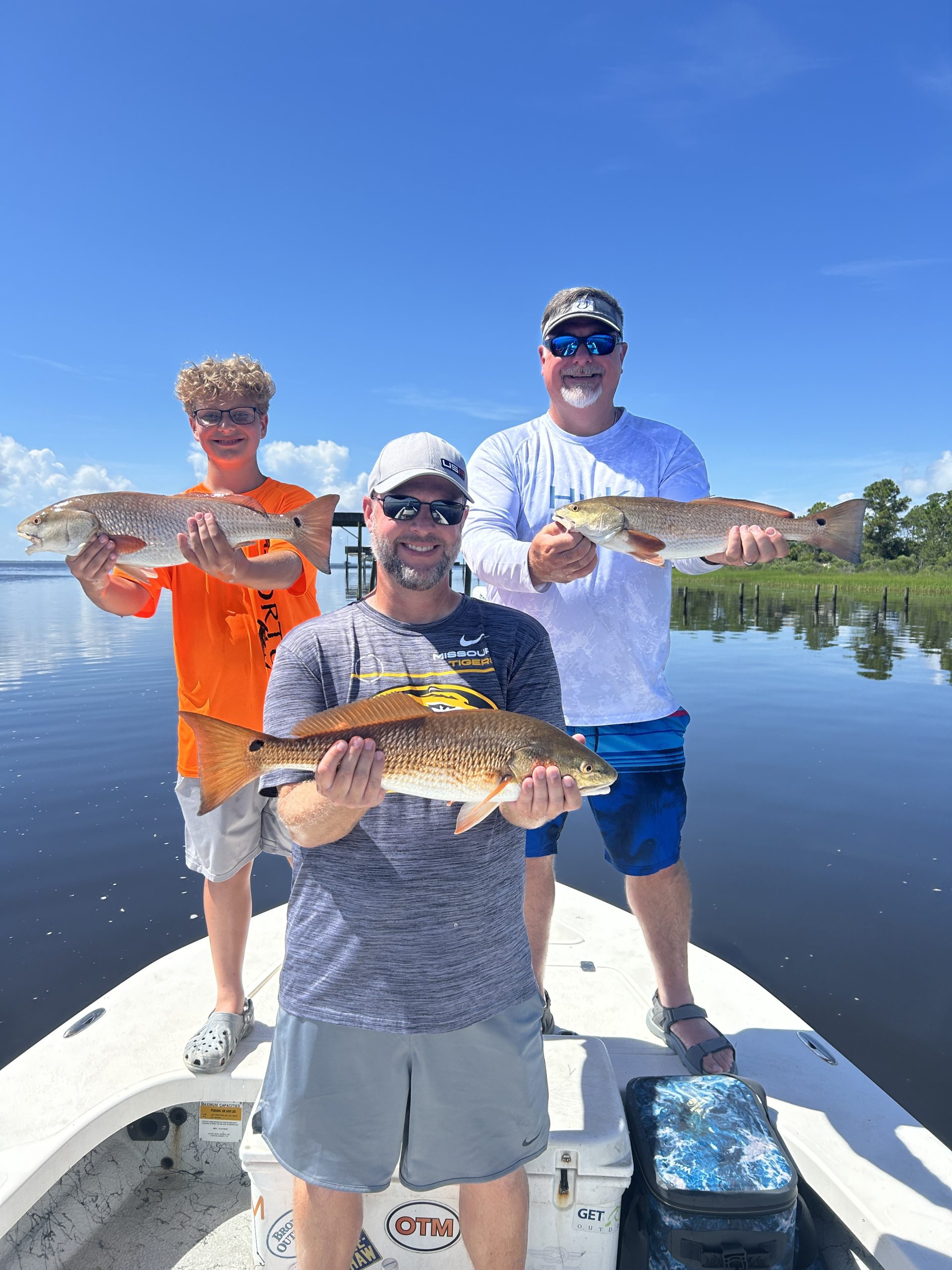 A happy family holding a Redfish during a 4-hour half-day fishing charter in Navarre Beach, Florida.