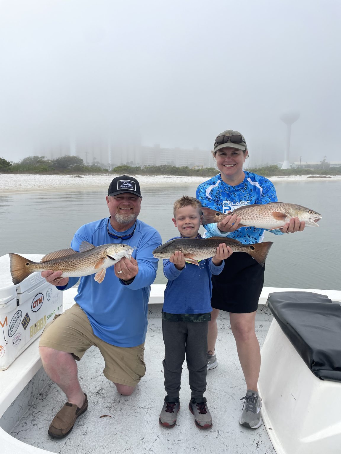 Family holding redfish on a foggy cool-weather charter in Santa Rosa Sound, Navarre Beach