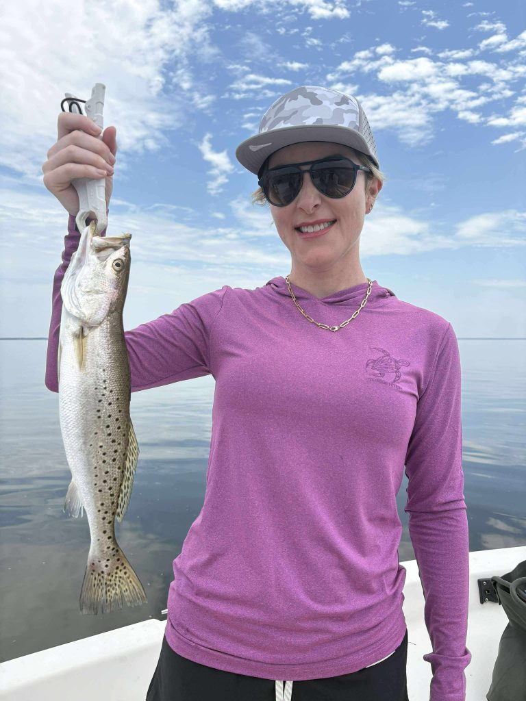 Angler holding a speckled trout on a half day trip near Navarre Beach